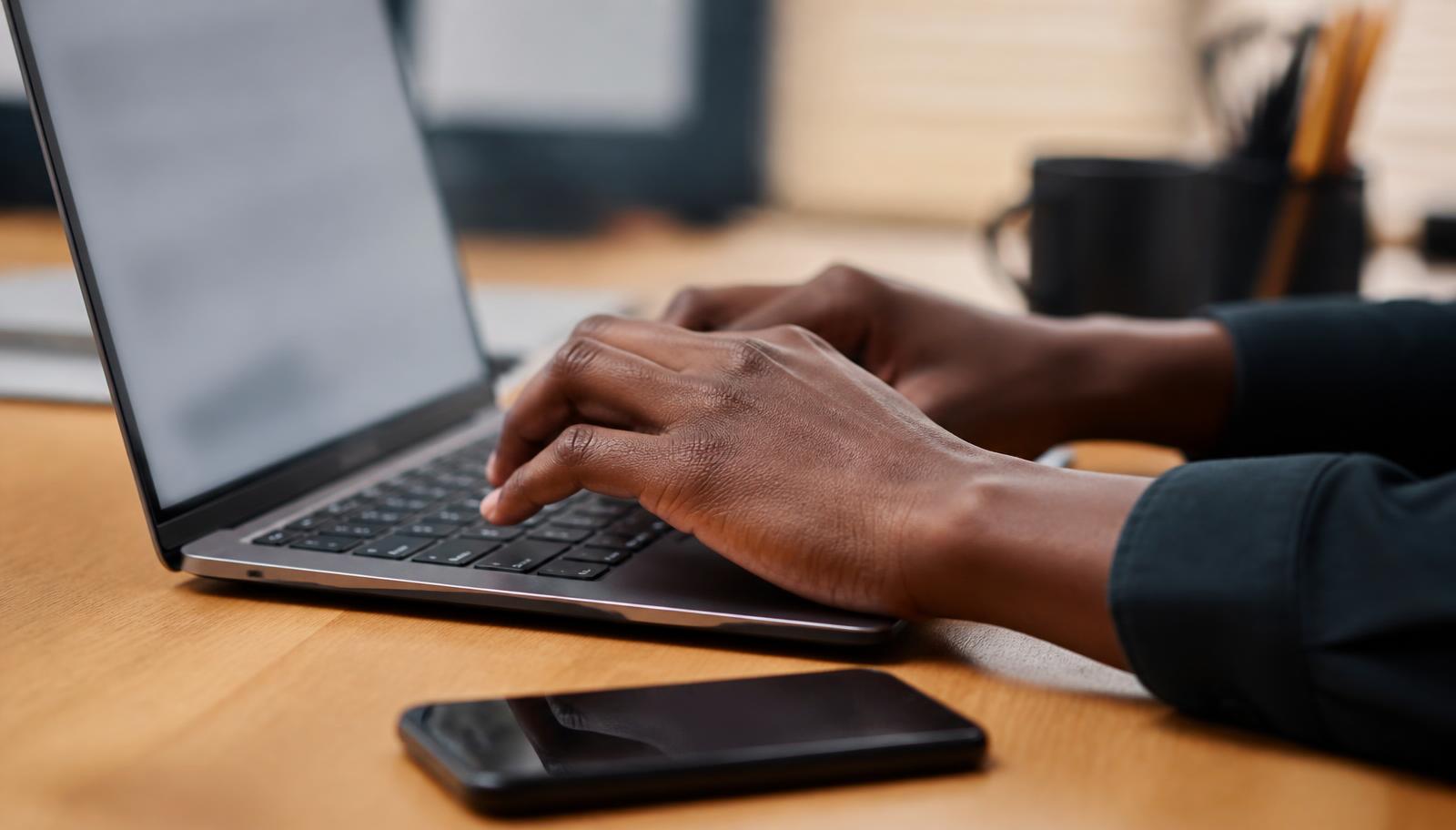 Someone starting a domain transfer on a laptop with a phone ready for the approval message